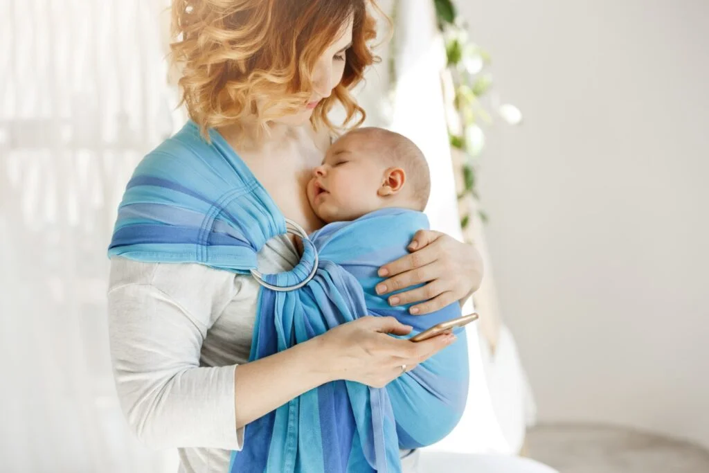 une maman qui porte son bébé dans une écharpe