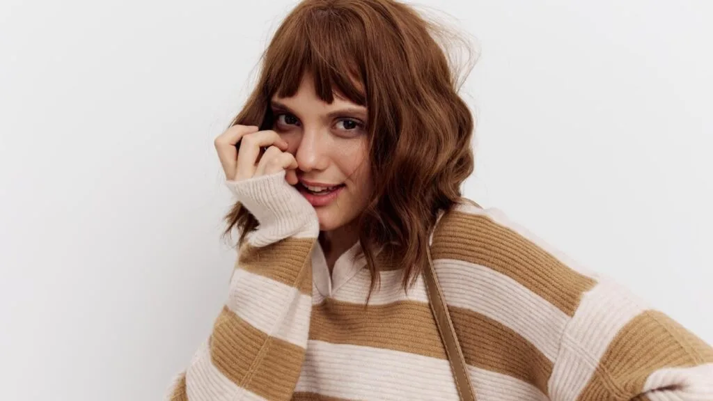 Frange rideau sur cheveux mi-longs, style automnal doux.