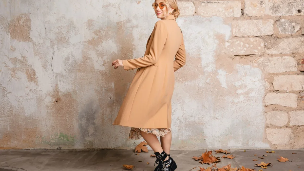 Silhouette féminine en manteau beige et jupe longue, tenue d’automne chic.