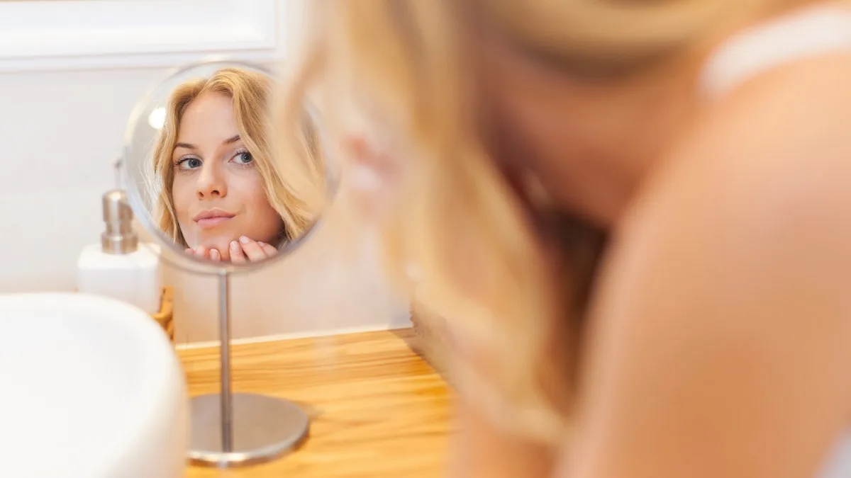 Femme qui se repoudre légèrement devant un miroir