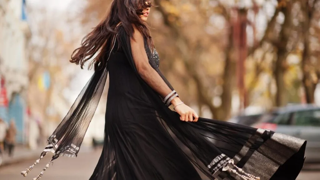 Femme en robe noire fluide avec choker discret, illustrant la tendance Soft Goth.