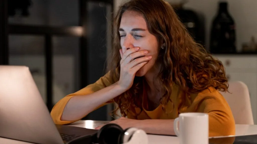 Femme fatiguée devant un ordinateur portable tard le soir, symbolisant la surcharge d’écrans et le burn-out digital.