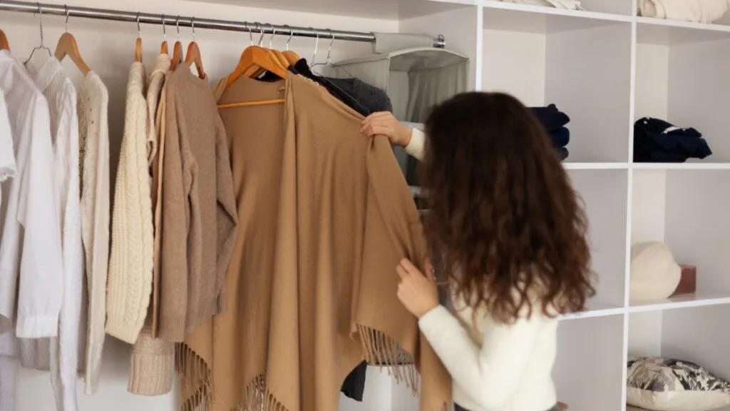 Capsule wardrobe d’hiver avec manteaux, pulls et jeans alignés dans un dressing d’hiver minimaliste