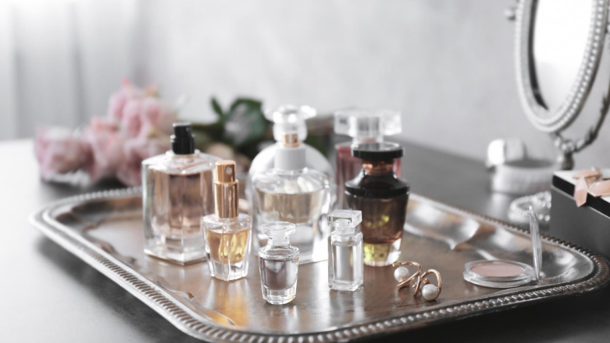 Plusieurs flacons de parfum posés sur une coiffeuse avec carnet de notes