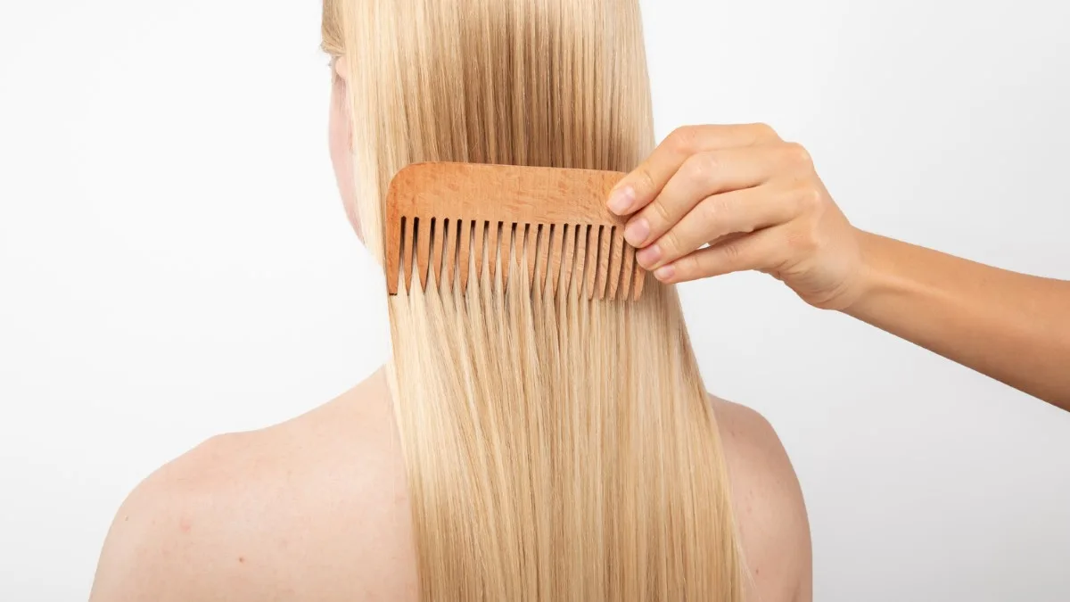 Gros plan sur un peigne à dents larges glissant dans des cheveux brillants