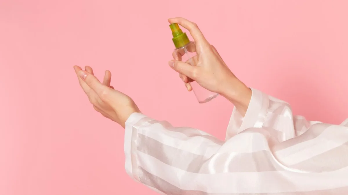 Main féminine vaporisant une fragrance florale sur le poignet