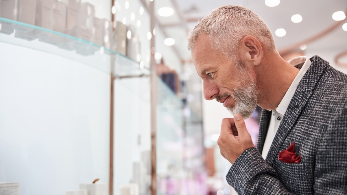 Homme devant une étagère de fragrances masculines boisées