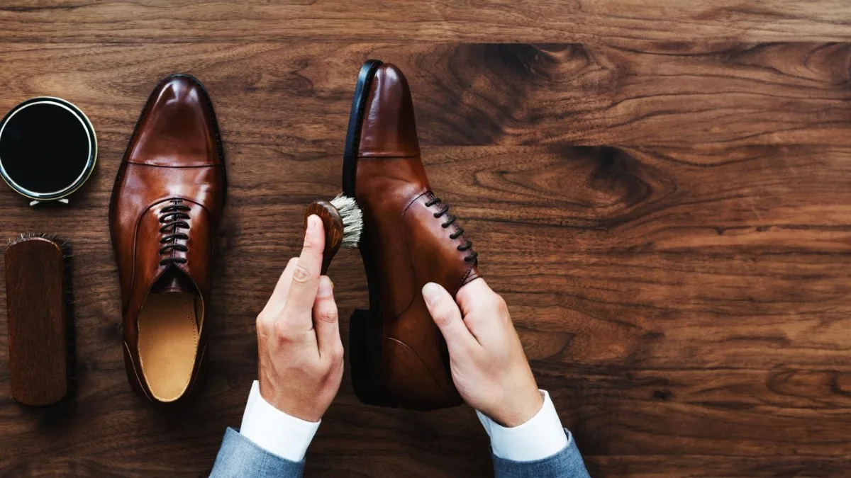 Mains cirant une paire de chaussures en cuir sur une table