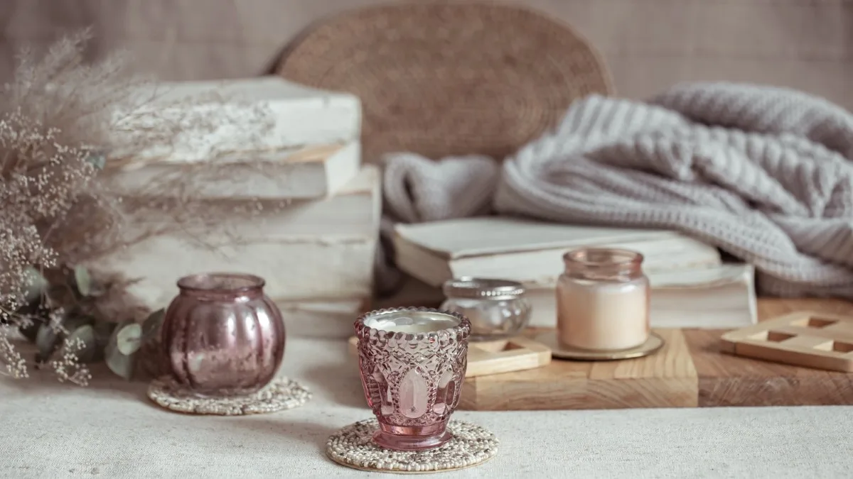 Bougie et produits de soin posés près d’une fenêtre, créant une ambiance cocoon pour la routine d’hiver