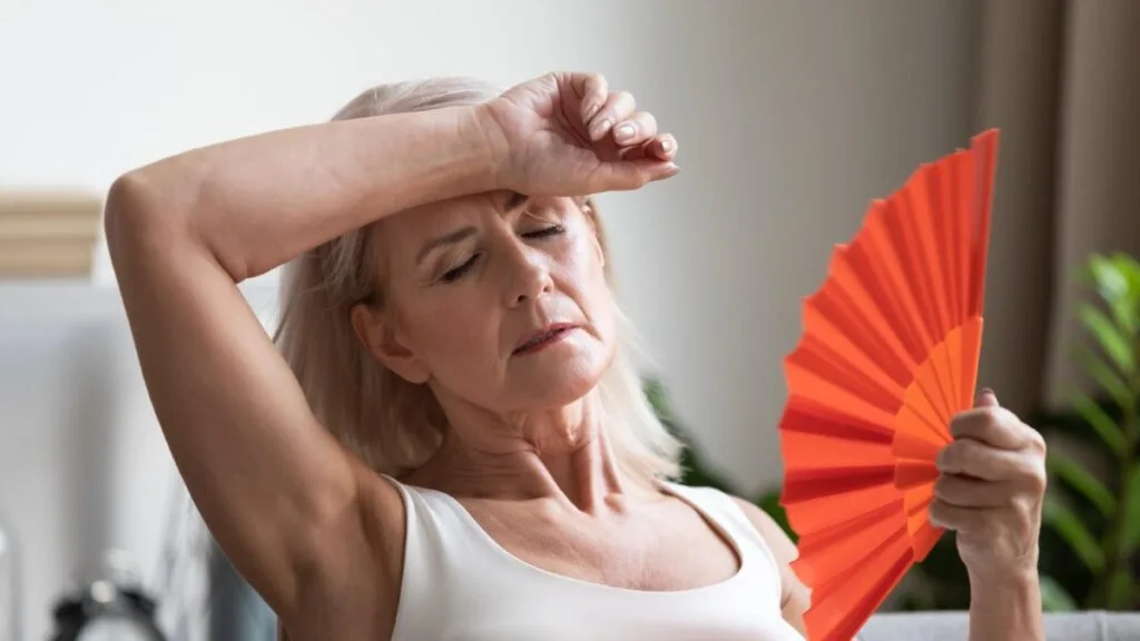 Femme en préménopause qui utilise un éventail car elle a chaud.