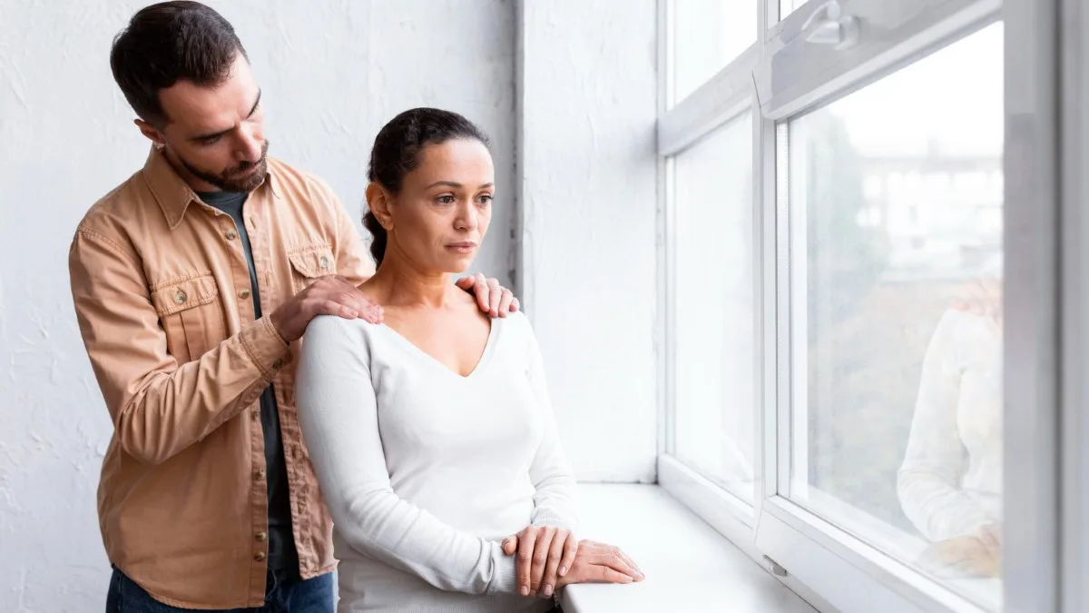 Parent pensif près d’une fenêtre, ambiance douce et introspective.