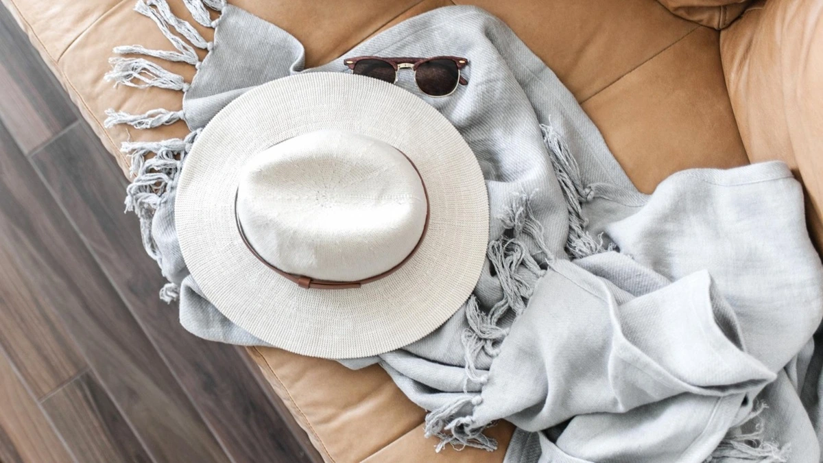 Écharpe légère, sac pratique, lunettes de soleil et veste fine posés sur une chaise dans un univers mode féminin.