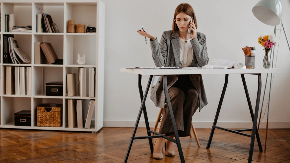 Femme au bureau avec top léger, gilet fin et trench dans une tenue pensée pour les fortes variations de température.