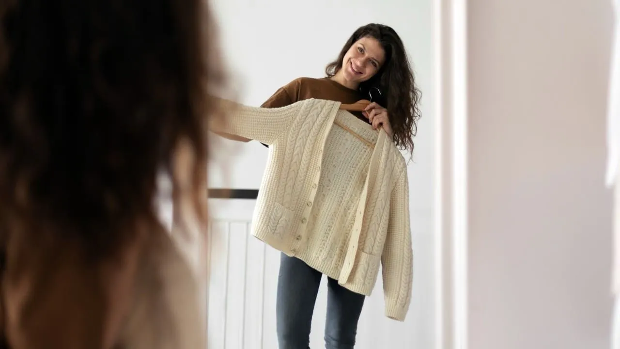 Femme essayant une veste devant un miroir dans une ambiance douce et féminine